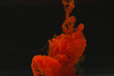 Sudaki parlak kırmızı mürekkebi kapat ve siyah arkaplanda kopya alanı oluştur. Mürekkep, sıvı, şekil ve renk kavramı.