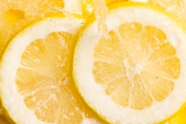 Limon dilimlerini suyla kapatın ve sarı arkaplanda kopya alanı olsun. Meyve, vejetaryen yemeği ve renk konsepti.