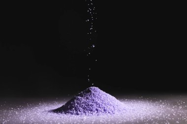 Mor kum yığınını kapat ve siyah arkaplana kopyala. Kum, doku, hareket, şekil ve renk kavramı.