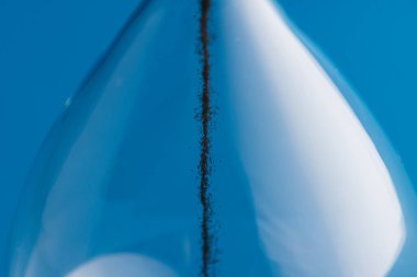 Kum saatini siyah kumla kapat ve mavi arkaplanda kopyala. Zaman, zaman tutma, şekil ve renk kavramı.