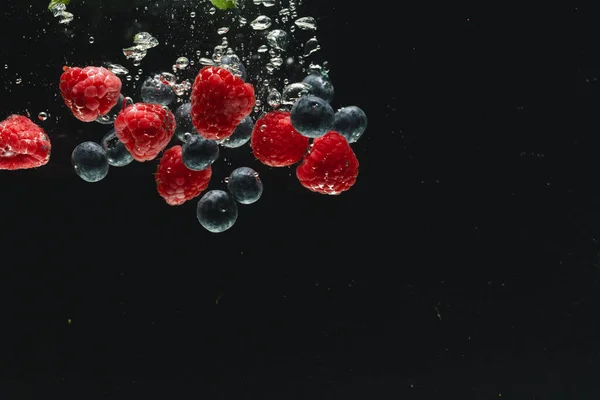 黒い背景のコピースペースで水に落ちる新鮮な果実のクローズアップ フルーツ ビーガンフード カラーコンセプト — ストック写真