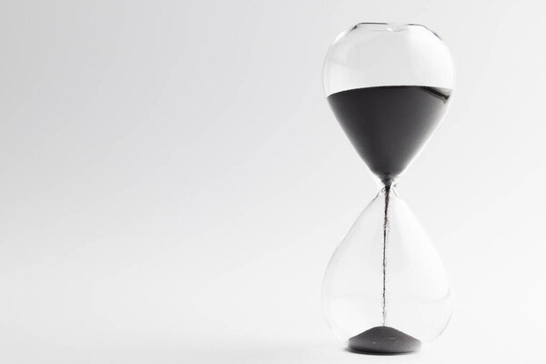 Close up of hourglass with black sand and copy space on white background. Time, timekeeping, shape and colour concept.