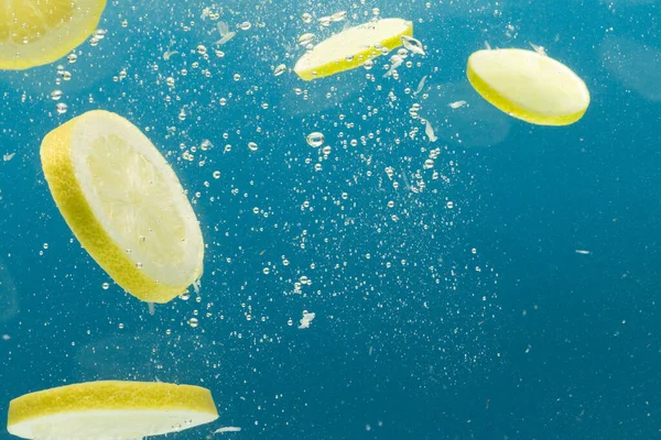 Nahaufnahme Von Zitronenscheiben Die Ins Wasser Fallen Mit Kopierraum Auf — Stockfoto
