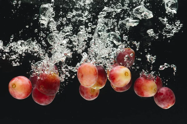 Zbliżenie Czerwonych Winogron Wpadających Wody Miejsca Kopiowania Czarnym Tle Owoce — Zdjęcie stockowe