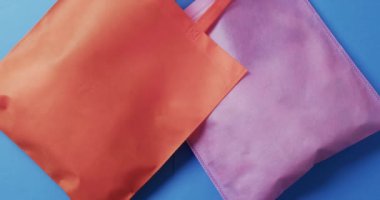 Kırmızı ve pembe tuval çantaların videosu. Mavi arkaplanda kopyalama alanı var. Çanta, alışveriş, moda ve kumaş konsepti.