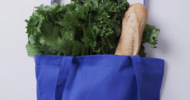 Maydanozlu, lahanalı ve baget ekmekli mavi tuval çantası, beyaz arka planda kopyalama alanı. Çanta, market, yiyecek, alışveriş ve kumaş konsepti.