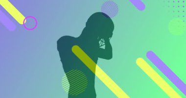 Yeşil arka plandaki erkek Amerikan futbolcusunun siluetinin üzerinde renkli şekillerin canlandırması. Spor, spor, soyut ve şablon konsepti dijital olarak oluşturulmuş video.