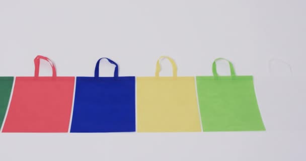 白い背景のコピースペースを備えた多色のキャンバスバッグの行のビデオ バッグ ショッピング ファッション ファブリックのコンセプト — ストック動画
