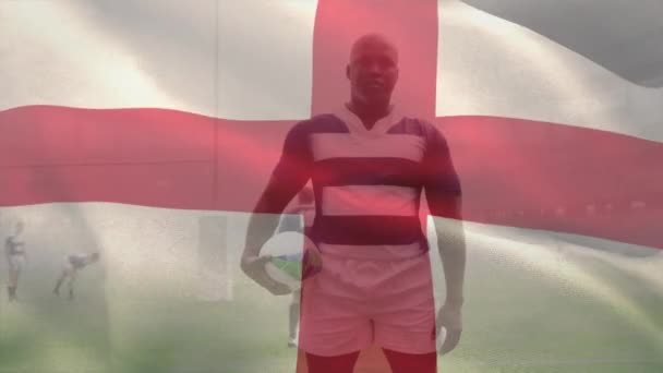 Animacja Flagi Anglii Machająca Nad Afrykańskim Amerykańskim Graczem Trzymającym Piłkę — Wideo stockowe