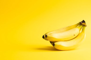 Muzları kapatın ve sarı arkaplanda kopyalayın. Meyve, egzotik meyve, yiyecek, tazelik ve renk kavramı.