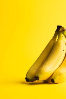 Muzları kapatın ve sarı arkaplanda kopyalayın. Meyve, egzotik meyve, yiyecek, tazelik ve renk kavramı.