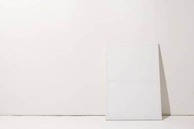 Beyaz tuval ve fotokopi alanı beyaz duvar arka planına yaslanıyor. İmza, yazma alanı ve reklam kavramı.