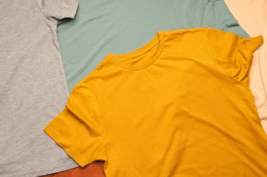 Çok renkli t-shirtler ve fotokopi alanı arkaplanlarının olduğu daireyi kapatın. Moda, kıyafetler, renk ve kumaş konsepti.