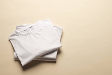 Katlanmış beyaz tişörtleri kapatın ve sarı arkaplanda yer açın. Moda, kıyafetler, renk ve kumaş konsepti.