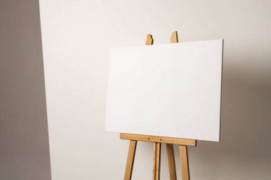 Ahşap sehpada beyaz tuval ve beyaz arka planda yer kopyalama. İmza, yazma alanı ve reklam kavramı.