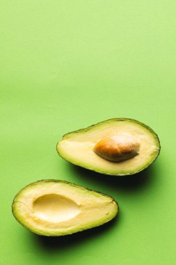 Avokadoyu yarıya indir ve yeşil arka plandaki boşluğu kopyala. Sebze, yiyecek, tazelik ve renk konsepti.