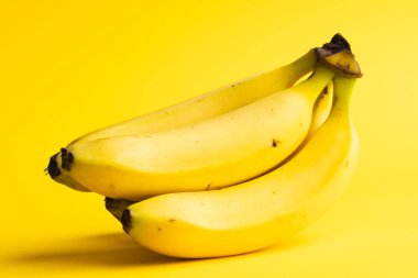 Muzları kapatın ve sarı arkaplanda kopyalayın. Meyve, egzotik meyve, yiyecek, tazelik ve renk kavramı.