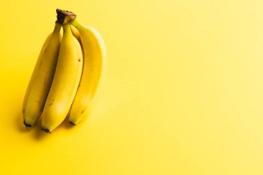 Muzları kapatın ve sarı arkaplanda kopyalayın. Meyve, egzotik meyve, yiyecek, tazelik ve renk kavramı.