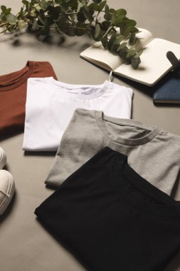 Çok renkli tişörtler, ayakkabılar ve arka planda fotokopi alanı olan not defterleri. Moda, kıyafetler, renk ve kumaş konsepti.