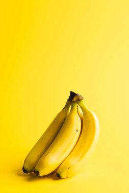 Muzları kapatın ve sarı arkaplanda kopyalayın. Meyve, egzotik meyve, yiyecek, tazelik ve renk kavramı.