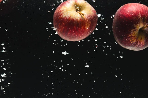 黒い背景のコピースペースで水に落ちる赤いリンゴのクローズアップ フルーツ 食べ物 新鮮さ カラーコンセプト — ストック写真