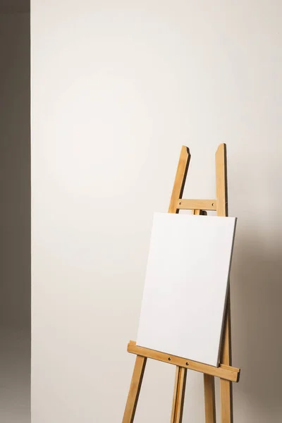 木製のイーゼルに白いキャンバスがあり 白い背景にスペースをコピーします サイネージ ライティングスペース 広告コンセプト — ストック写真