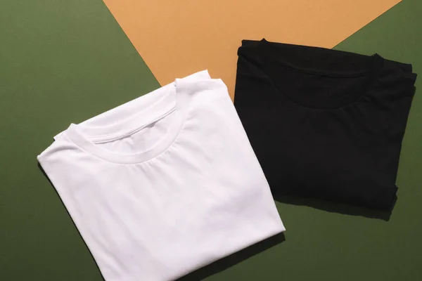 紧贴折叠的白色和黑色T恤 复制绿色到橙色背景的空间 色彩和面料概念 — 图库照片