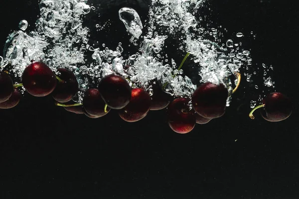黒い背景のコピースペースで水に落ちるチェリーの近く フルーツ 食べ物 新鮮さ カラーコンセプト — ストック写真