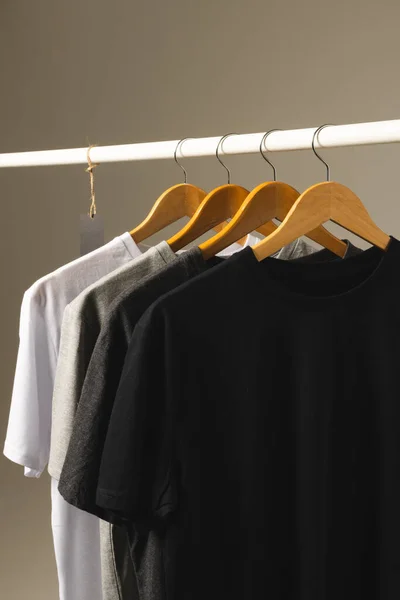 衣服の柵から掛かるハンガーの4つのTシャツは灰色の背景のスペースをコピーします ファッション ファブリックコンセプト — ストック写真