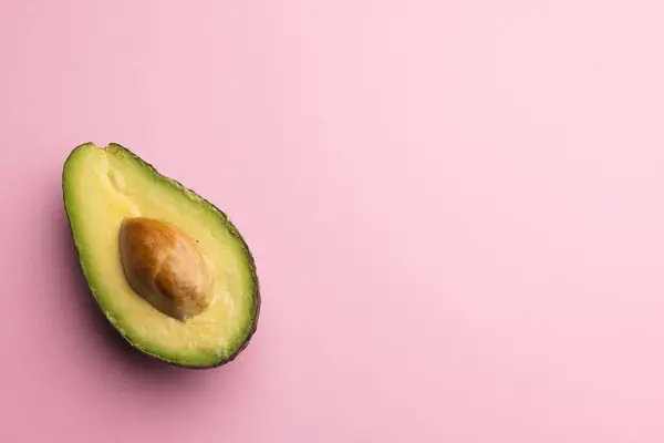 stock image Close up of half of avocado and copy space on pink background. Vegetable, food, freshness and colour concept.