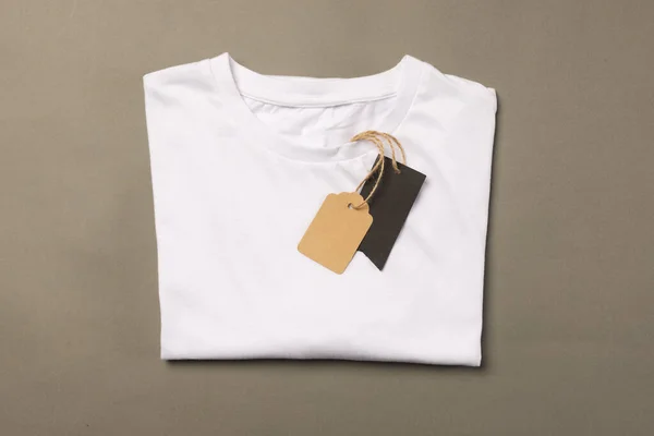 折叠式白色T恤 带有标签 带有褐色背景的复制空间 色彩和面料概念 — 图库照片