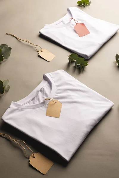 Opgevouwen Witte Shirts Met Tags Blaadjes Met Kopieerruimte Bruine Achtergrond — Stockfoto