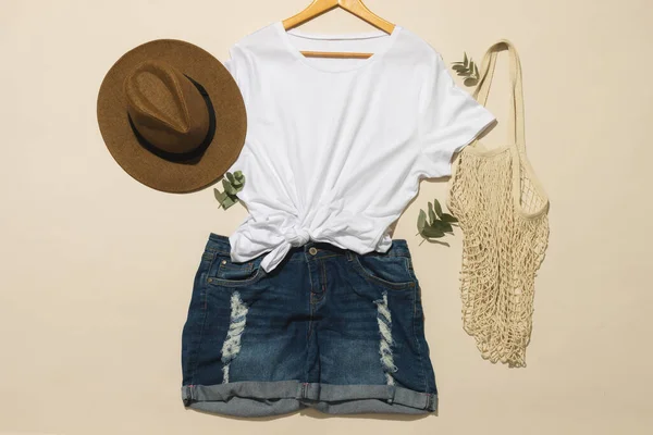 平铺白色T恤 太阳帽 网袋和斜纹棉布短裤 在奶油背景上的复制空间 色彩和面料概念 — 图库照片