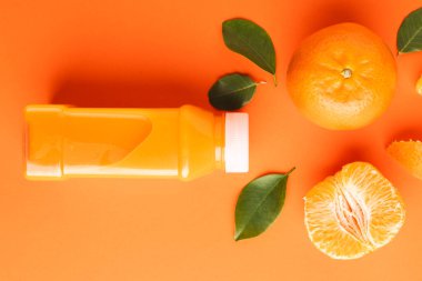 Meyve suyu, mandalina, segmentler ve turuncu arka planda kopya alanı olan yapraklarla şişeyi kapat. Meyve, yemek, tazelik ve renk kavramı.