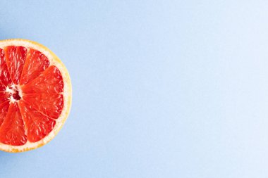 Kırmızı greyfurtun yarısını kapat ve mavi arkaplana kopyala. Meyve, yemek, tazelik ve renk kavramı.