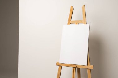 Ahşap sehpada beyaz tuval ve beyaz arka planda yer kopyalama. İmza, yazma alanı ve reklam kavramı.