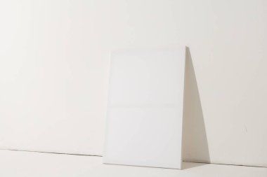 Beyaz tuval ve fotokopi alanı beyaz duvar arka planına yaslanıyor. İmza, yazma alanı ve reklam kavramı.