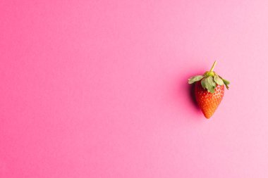 Çileği kapat ve pembe arka plandaki boşluğu kopyala. Meyve, meyve, yiyecek, tazelik ve renk kavramı.