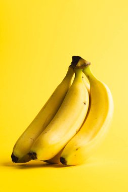 Muzları kapatın ve sarı arkaplanda kopyalayın. Meyve, egzotik meyve, yiyecek, tazelik ve renk kavramı.