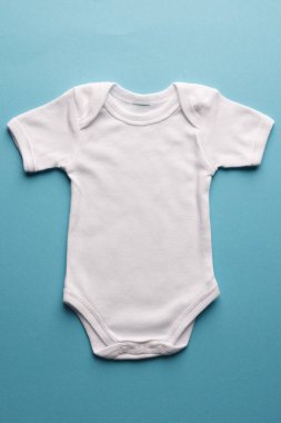 Mavi arka planda fotokopi alanı olan düz beyaz bebek yatağı. Bebek modası, kıyafetler, renk ve kumaş konsepti.