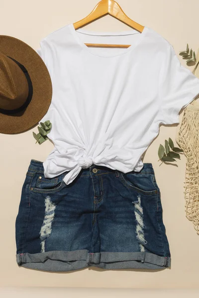 白いTシャツの平らな層 日当たり 網袋およびデニム ショーツ クリームの背景のコピー スペース ファッション ファブリックコンセプト — ストック写真