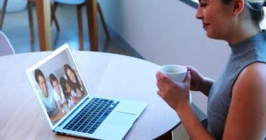 Beyaz bir kadın laptopunda ailesi, ebeveynleri ve iki çocuğu ile video görüşmesi yapıyor. Sosyal tecrit ve karantina süresince internetten etkileşime geçiyorlar..