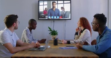 Çok ırklı erkek ve kadın yaratıcı iş arkadaşlarıyla bir toplantıda video konferans sırasında iş ortaklarıyla sohbet ediyorlar. İş teknolojisi iletişimi.
