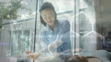 Asyalı kadın fizyoterapist ve kadın hasta üzerinde veri işleme animasyonu. Küresel sağlık, bilim, tıp, araştırma, bilgisayar ve veri işleme kavramı dijital olarak oluşturulmuş video.