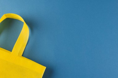 Mavi arkaplanda kopya alanı olan sarı brandayı kapat. Alışveriş, çanta, renk, kumaş, doku ve malzeme kavramı.