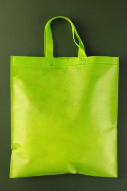 Koyu yeşil arka planda fotokopi alanı olan yeşil tuval. Alışveriş, çanta, renk, kumaş, doku ve malzeme kavramı.