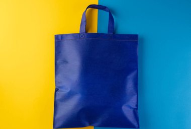 Sarı ve mavi arkaplanda kopya alanı olan mavi brandayı kapat. Alışveriş, çanta, renk, kumaş, doku ve malzeme kavramı.
