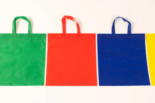 白い背景のコピースペースが付いている多色のキャンバスの袋の列 ショッピング バッグ カラー ファブリック テクスチャ 素材コンセプト — ストック写真