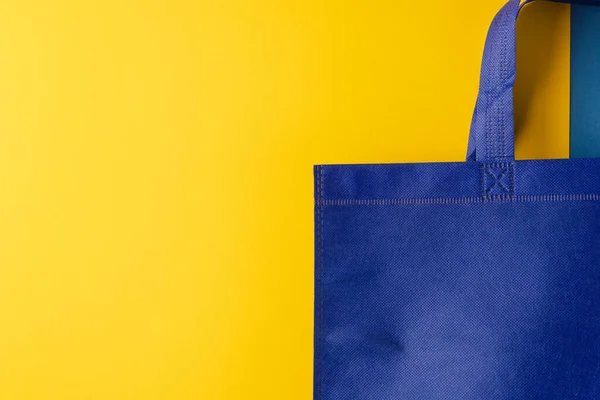 黄色の背景にコピースペースを持つ青いキャンバスバッグのクローズアップ ショッピング バッグ カラー ファブリック テクスチャ 素材コンセプト — ストック写真