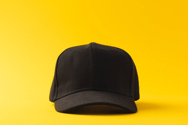 Black baseball cap and copy space on yellow background. Fashion, clothes, colour and fabric concept.